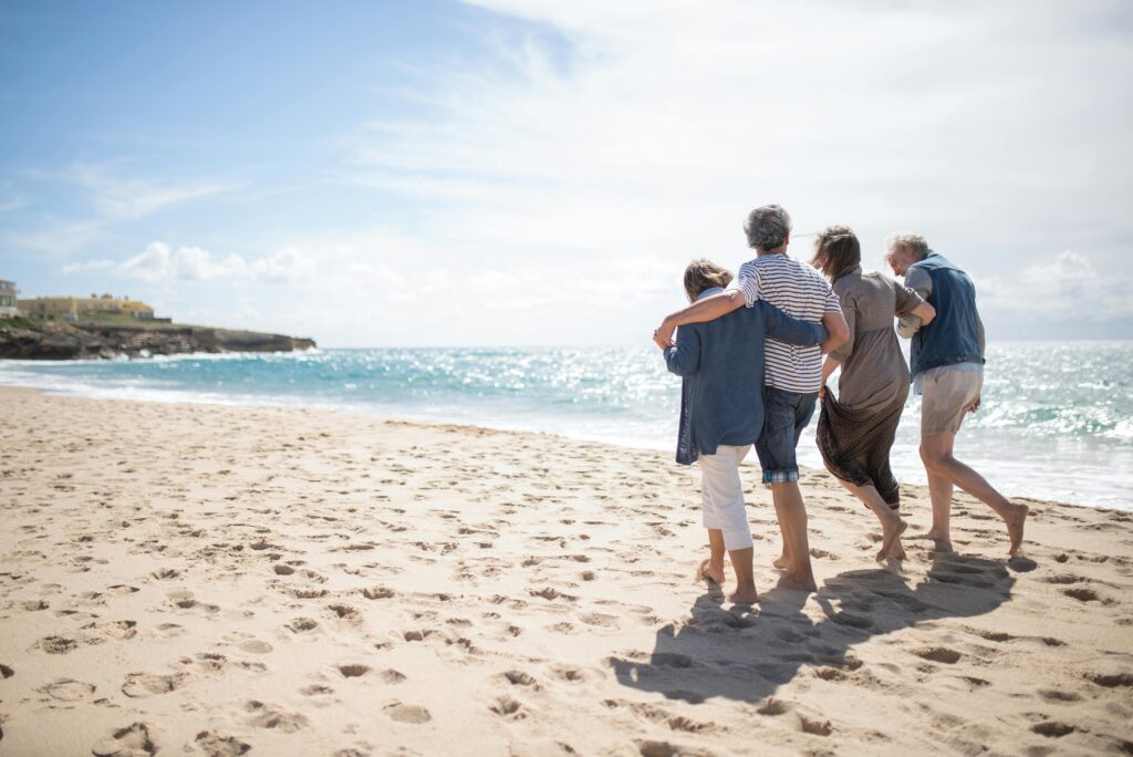 A family enjoys a casual walk along a sandy Portuguese beach on a sunny day.