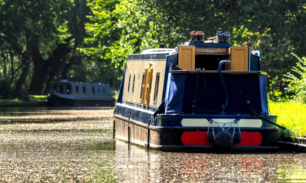Charming view of a narrowboat on a sunlit canal in Trevor, Wales, capturing summer travel vibes.
