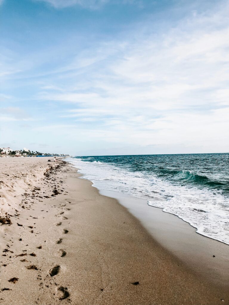 A serene beach with gentle ocean waves under a bright blue sky, perfect for a summer vacation.