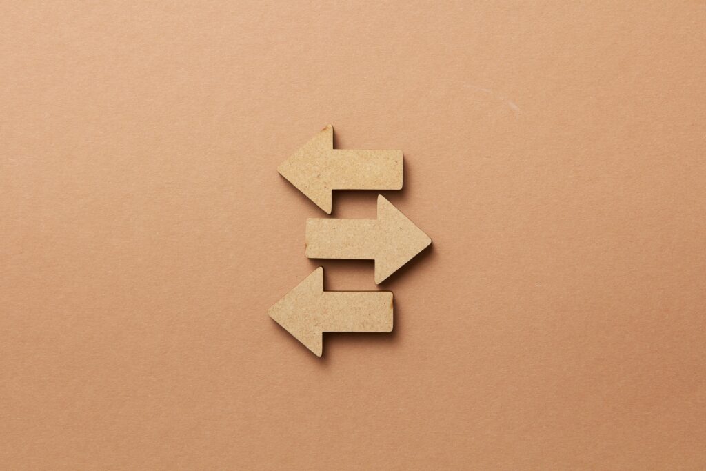 Close-up of three wooden arrows pointing in opposite directions on a beige surface.
